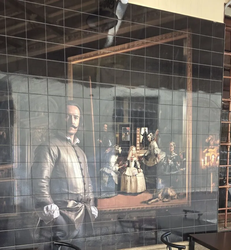 Tile mural in the passage: a painter in a dark doublet beside a court scene with a young princess and her maids